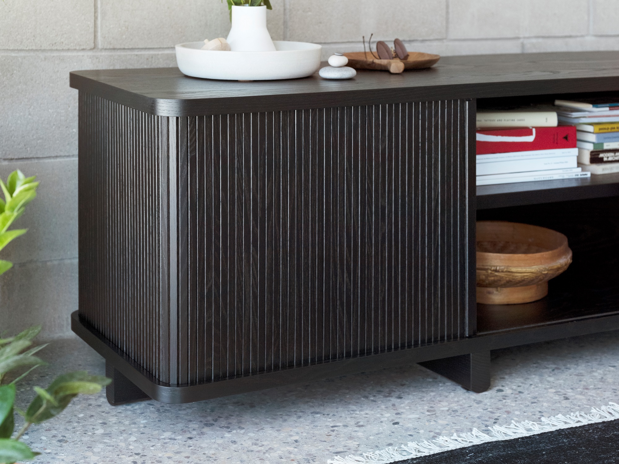 The Tambour mid century media console in black with books on inner shelf and vase and display bowls on top